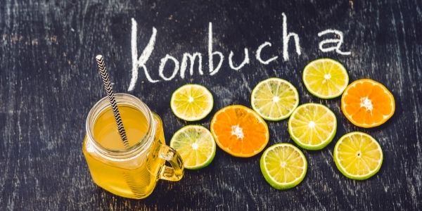table with fruit slices on it a drink and the words kombucha in chalk