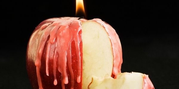 an apple turned into a candle with wax dripping down the apple