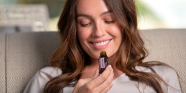 lady sitting on couch with bottle of doterra lavender oil