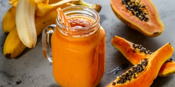 papaya smoothie with papaya on the side and bananas