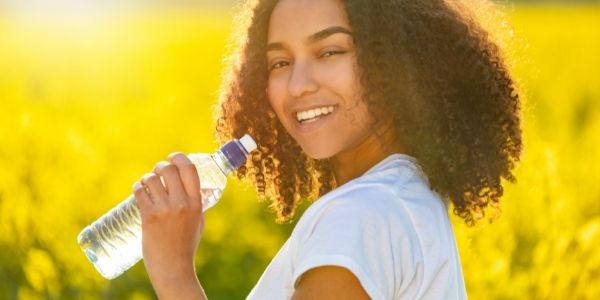women in a field drinking bottled water