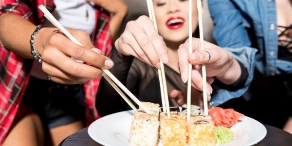 three people eating sushi