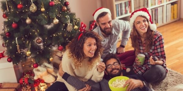 two couples watching something christmas tree in a background
