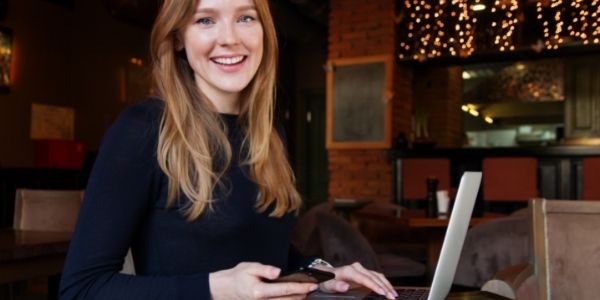 lady working on phone and laptop at a coffee shop