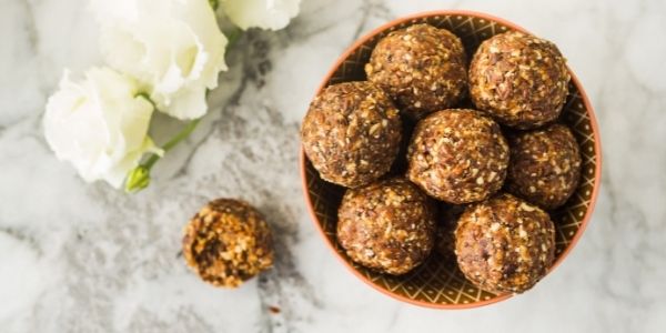 chocolate peanut butter balls in a bowl beside some white flowers