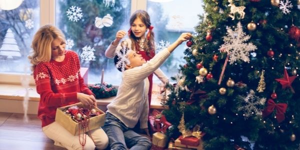 mom and two kids decorating christmas tree