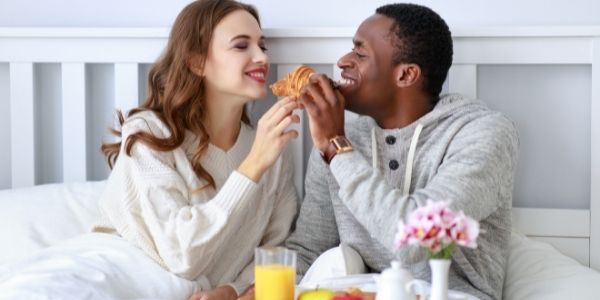 couple in bed eating breakfast