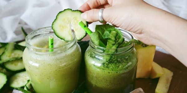 two jars with green smoothies cucumber and spinach