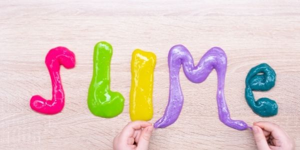 the word slime spelled out on a table with different color slime for each letter