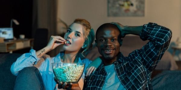 two people cuddling on couch eating popcorn
