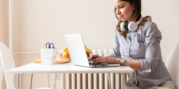 women sitting at kitchen table typing on laptop