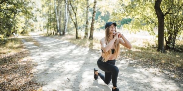 lady outside on a trail doing lunges