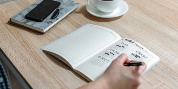 man writing goals in notebook