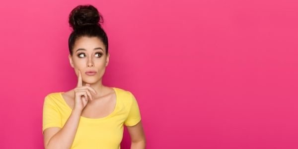 girl with yellow shirt standing against bright pink background