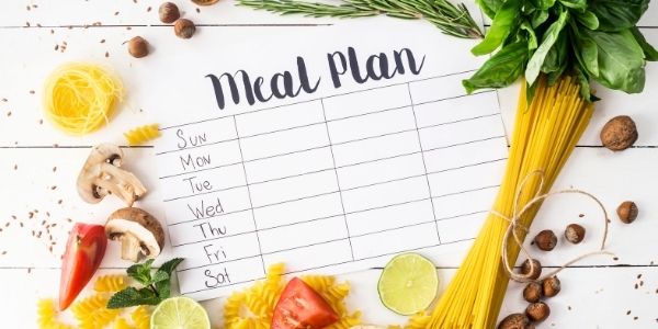 weekly meal plan surrounded by vegetables