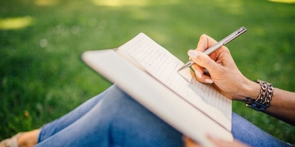 lady sitting on grass journaling