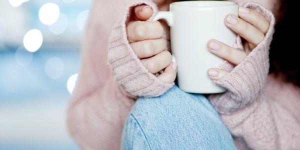 lady in pink sweater and jeans holding a mug
