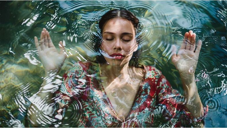 women floating in water with palms up